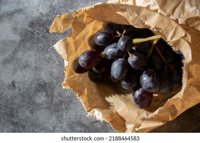 Black Grapes In A Brown Paper Bag. Eco Friendly Recycle Packaging To Help Tackle Global Warming