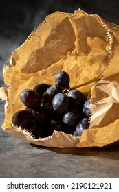 Black Grapes In A Brown Paper Bag. Eco Friendly Recycle Packaging To Help Tackle Global Warming