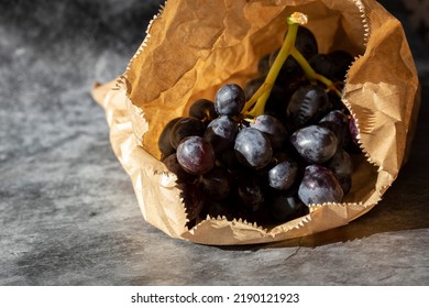 Black Grapes In A Brown Paper Bag. Eco Friendly Recycle Packaging To Help Tackle Global Warming