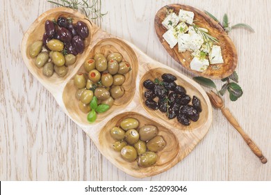 Black and green olives with feta cheese. Assorted olives and feta or goat cheese cheese in olive tree dish on wooden table - Powered by Shutterstock