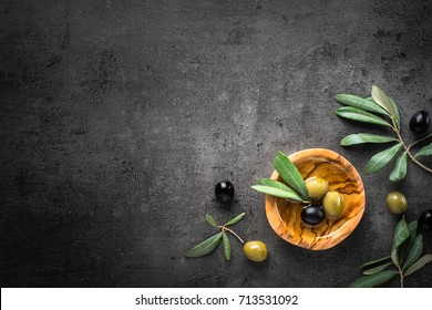 Black And Green Olives And Oil  In Wooden Bowl On Black Slate Background. Top View  With Space For Text.