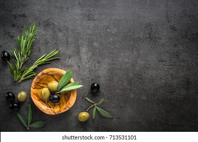 Black And Green Olives And Oil  In Wooden Bowl On Black Slate Background. Top View  With Space For Text.