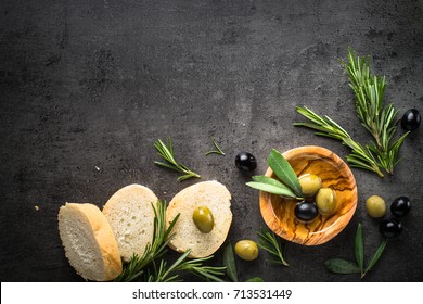 Black And Green Olives Olive Oil And Bread On Black Slate Background. Top View  With Space For Text.