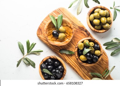 Black And Green Olives In Wooden Bowls And Olive Oil Bottle. Top View On White Background With Space For Text.