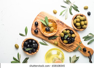 Black And Green Olives In Wooden Bowls And Olive Oil Bottle. Top View On White Background.