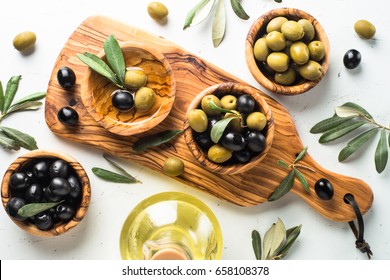 Black And Green Olives In Wooden Bowls And Olive Oil Bottle. Top View On White Background.