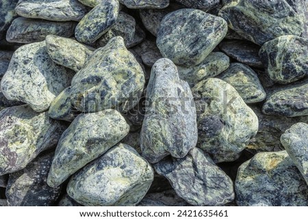 Black green pebbles closeup. Decorative marble stones of rounded shape. Use green marble to beautify your garden, complete your landscaping, for patios, and indoors. Building materials