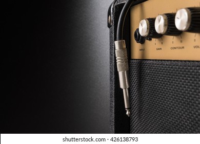 Black guitar amplifier with jack cable on black  background