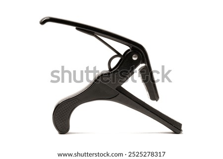 A black guitar capo, designed to raise or lower the pitch by clamping onto the fretboard. With this capo, you can easily change keys without retuning your guitar. Photographed on a white background.