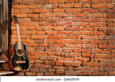 black guitar on the steps with brick background horizontal