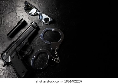 Black Gun, Flashlight, Glasses And Police Metal Real Handcuffs Lie On The Black Background. Private Detective Work. Searching Information. Crime And Robbery, Prison Concept.