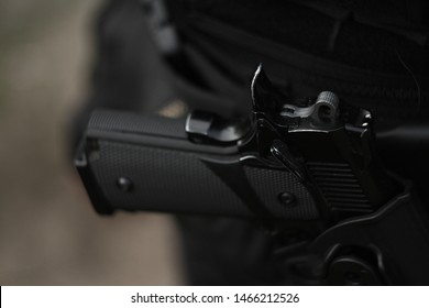 black gun in a holster on the belt of a man with a blurred photon shutter hook