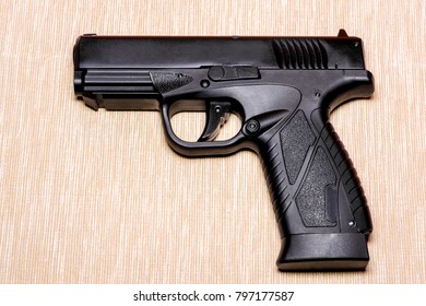 Black gun isolated on light coloured background.