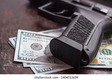 Black Gun On American Dollars Background. Military Industry, War, Global Arms Trade, Weapon Sale, Contract Killing And Crime Concept