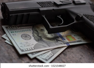 Black Gun On American Dollars Background. Military Industry, War, Global Arms Trade, Weapon Sale, Contract Killing And Crime Concept