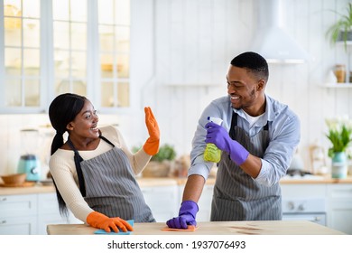 Black Guy Being Silly During House Cleanup, Pretending To Spray His Girlfriend From Detergent Bottle At Kitchen