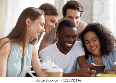 Black guy holding mobile phone watching funny videos with mixed race friends having fun together. Laughing students taking selfie photo looking at cellular screen. Friendship, technology usage concept - Powered by Shutterstock