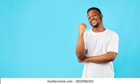 Black Guy Pointing Thumb Aside At Blank Space For Text Standing On Blue Studio Background. Look There Concept. Panorama - Shutterstock ID 1810986352