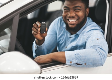 Black Guy Showing Car Key Smiling To Camera Sitting In New Automobile. Happy Auto Buyer. Selective Focus