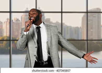 Black Guy Sings Into Microphone. Young Singer On City Background. So Much Passion. Audience Will Be Charmed.