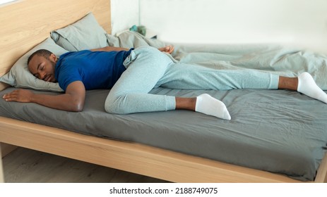 Black Guy Sleeping Lying On Stomach On Bed In Bedroom Indoor. Millennial Man Resting Napping Peacefully At Home. Healthy Sleep, Rest And Relaxation Concept. Panorama