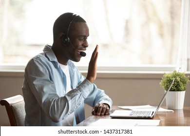 Black guy wear headset start lesson online look at laptop screen wave hand greeting tutor improves foreign language knowledge get skills through internet, education distantly using modern tech concept - Shutterstock ID 1437317381