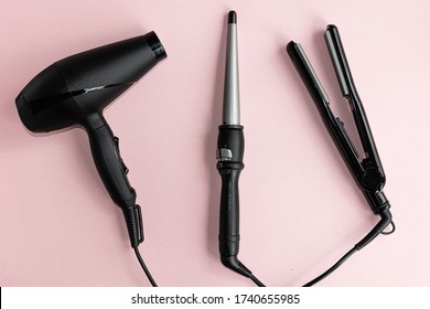  Black hair dryer, curling iron and hair iron on a pink background. 
Professional hairdresser set. Tools necessary for hair care. - Powered by Shutterstock