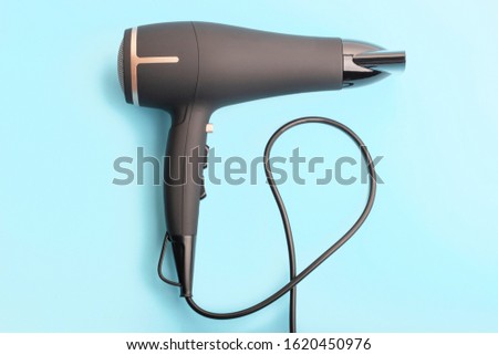 Black hair dryer on a blue background close-up top view.