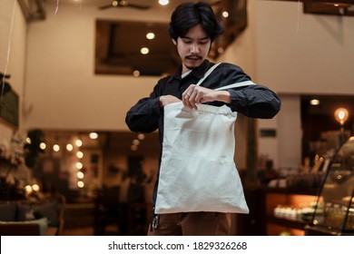 Black Hair Guy Find Something Inside The White Canvas Bag.