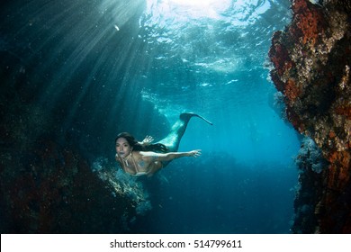 Black Hair Mermaid Swimming Underwater In The Deep Blue Sea