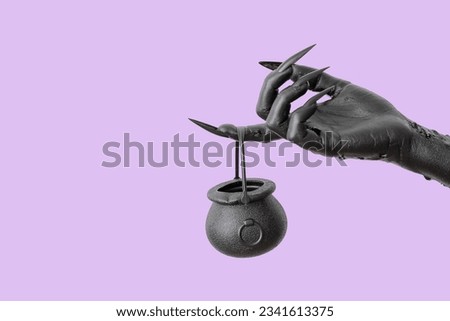 Black hand of witch and cauldron on purple background. Halloween celebration
