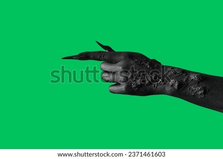 Black hand of witch pointing at something on green background. Halloween celebration