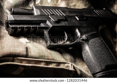 Black Handgun with Dramatic Lighting on Multicam Uniform Backdrop