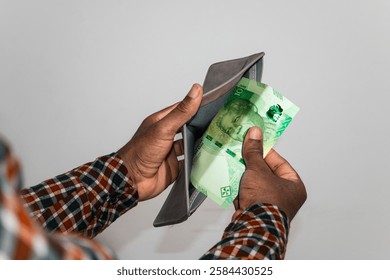 Black hands Holding empty opened men wallet containing single South African Rand  note. hand removing money out of wallet. no money poor person concept 