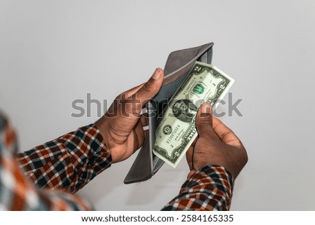 Black hands Holding empty opened men wallet containing single Two US dollar note. hand removing money out of wallet. no money poor person concept 