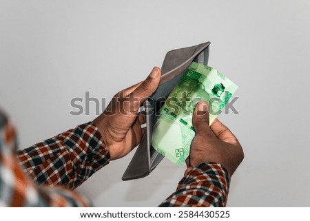 Black hands Holding empty opened men wallet containing single South African Rand  note. hand removing money out of wallet. no money poor person concept 