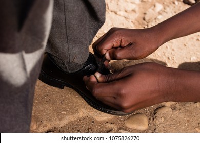 Black Hands Tieing Black School Shoes.