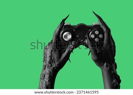 Black hands of witch with game pad on green background. Halloween celebration