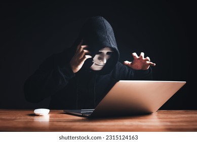 Black hat hacker in hood using laptop computer and call smartphone to victim on desk hacking privacy sensitive data hack in dark room background. Cyber security cyber crime concept. Hacking phishing - Powered by Shutterstock