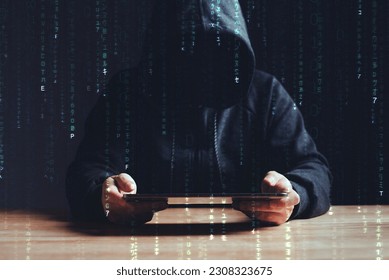 Black hat hacker using tablet on table where sensitive data is hacked in a dark room background with matrix binary rain code. Cyber security and cyber crime concept. Hacking and phishing