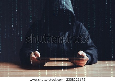 Black hat hacker using tablet on table where sensitive data is hacked in a dark room background with matrix binary rain code. Cyber security and cyber crime concept. Hacking and phishing