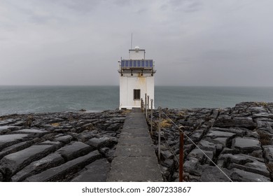 Black Head Lighthouse under a dramatic cloudy sky on the Irish coast