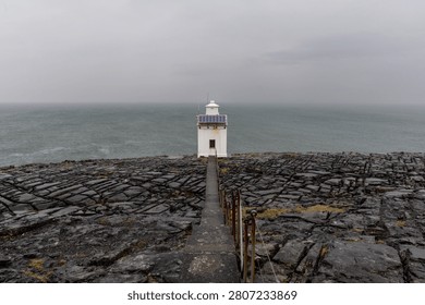 Black Head Lighthouse under a dramatic cloudy sky on the Irish coast