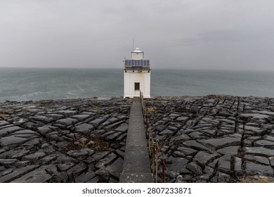 Black Head Lighthouse under a dramatic cloudy sky on the Irish coast