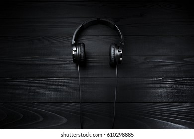 Black headphones on brown wooden dark background - Shutterstock ID 610298885