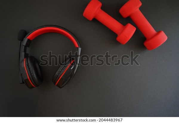   
       Black headphones with red stripes and bright red rubber
dumbbells on a black background                      

