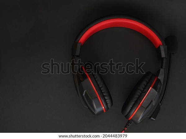 Black headphones with red\
stripes and a microphone on a black background                     \
         