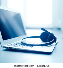 Black Headset Over White Laptop On The Wooden Table