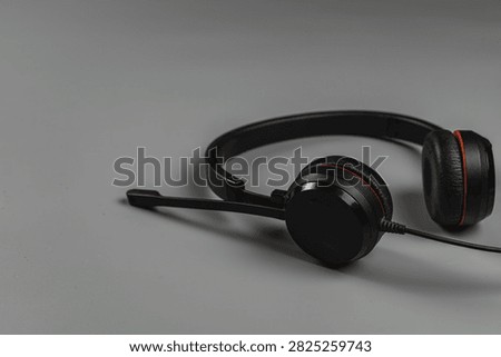 A black headset rests on a gray surface meant for sound and communication at work. It is ready for online calls.