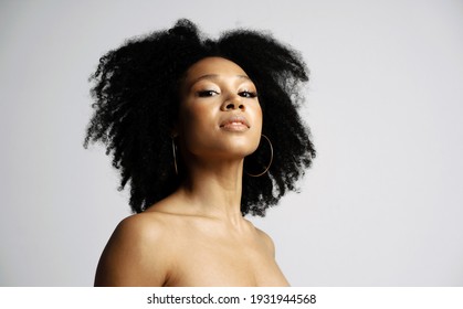 Black Healthy Curly Hair. Clean, Even Skin Of The Face. Portrait Of A Female Model Of Latin American Appearance. Photo Shoot In A Photo Studio On A White Background.